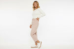 Woman wearing a white sweater and pink slim barrel pants 
 on a white background