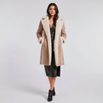 Woman wearing a beige coat with white fur trim on a white background