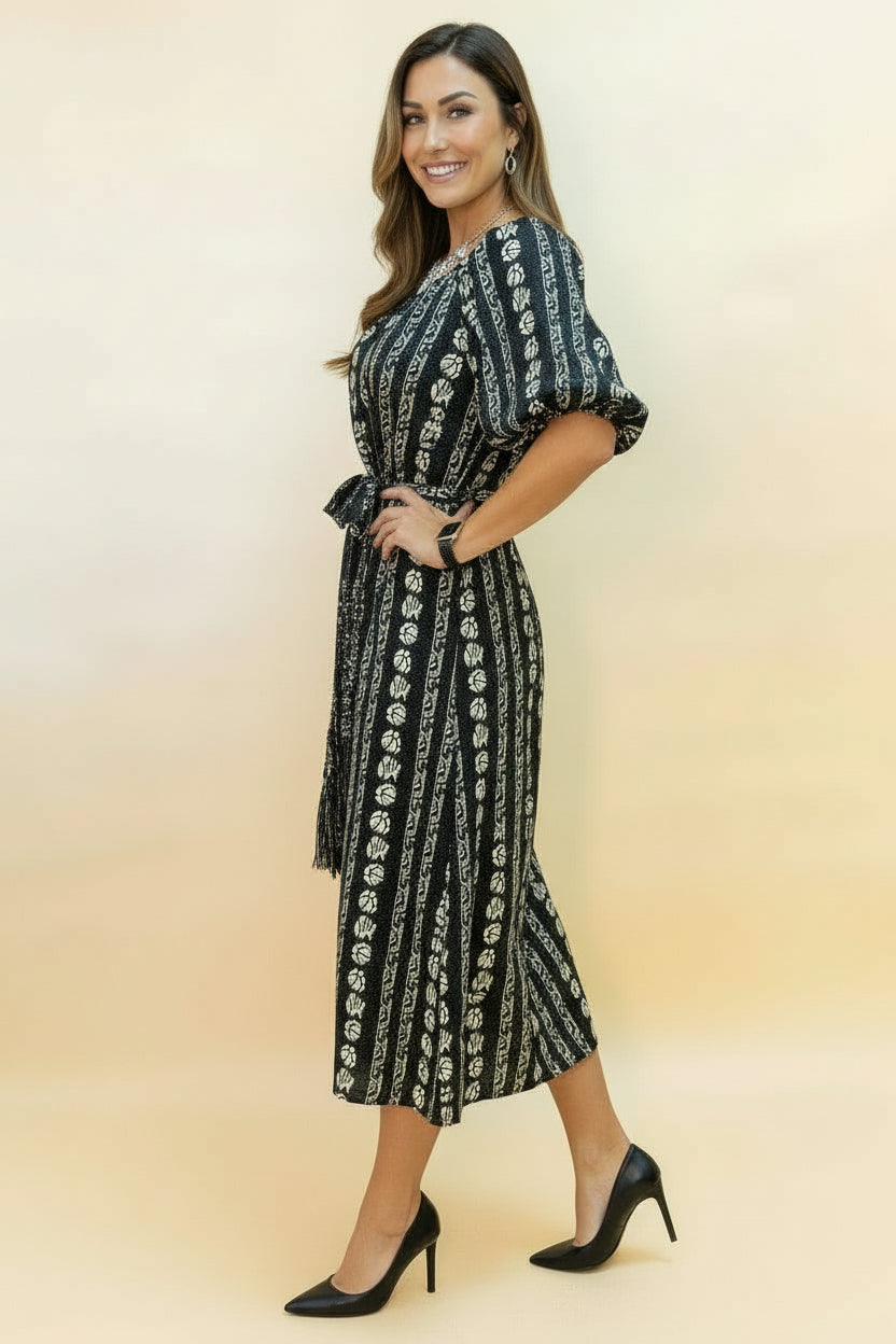 Woman wearing a black and white patterned dress with a black hat on a beige background