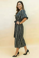 Woman wearing a black and white patterned dress with a black hat on a beige background