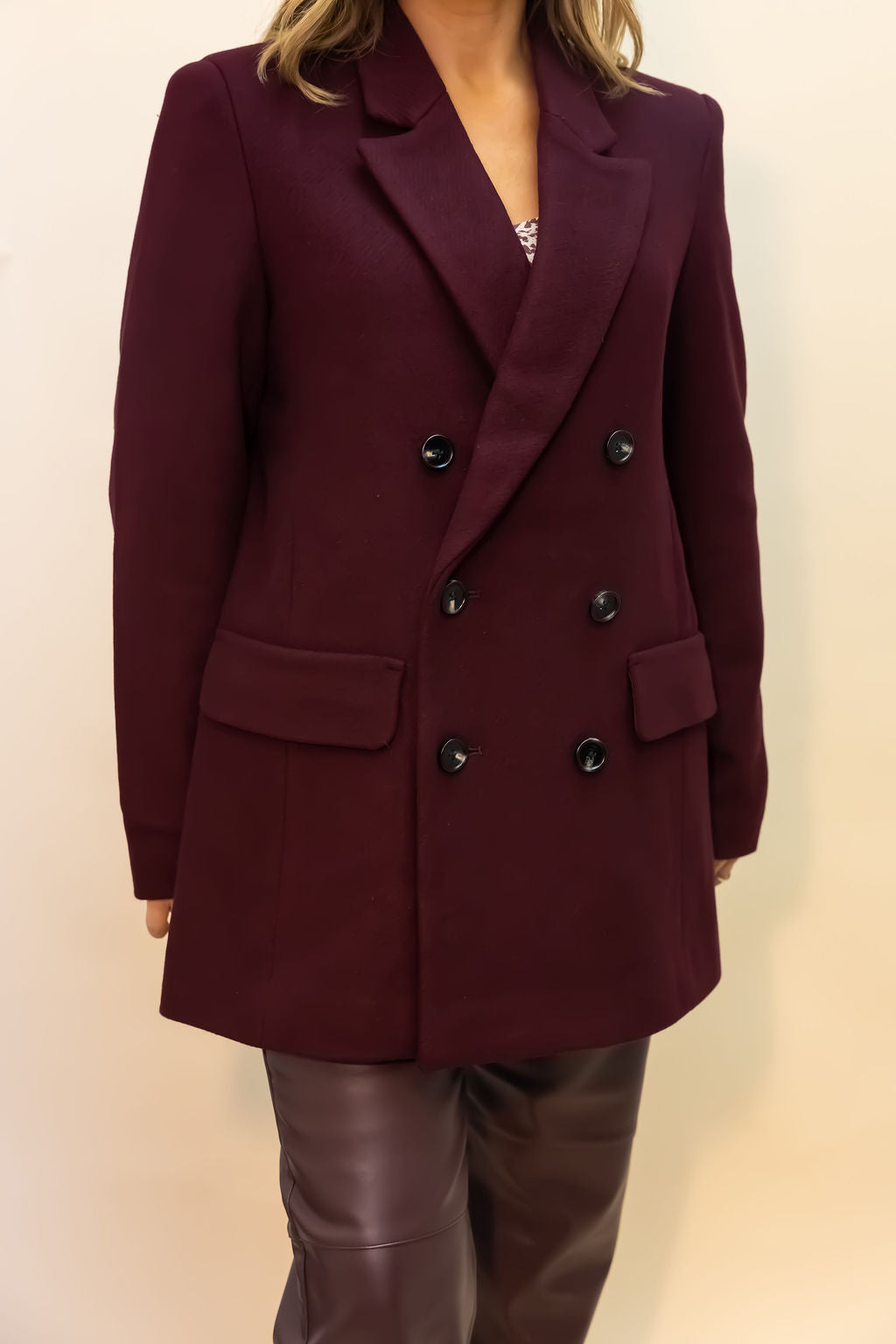 Maroon coat with black buttons on a plain background