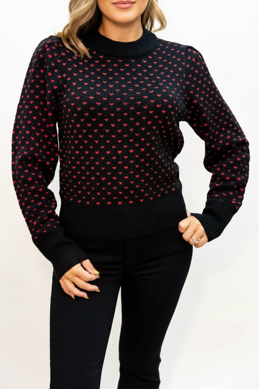 Black sweater with red pattern worn by a person on a beige background