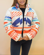 Woman wearing a colorful jacket with geometric patterns on a beige background