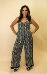 Woman wearing a black and white patterned jumpsuit on a beige background