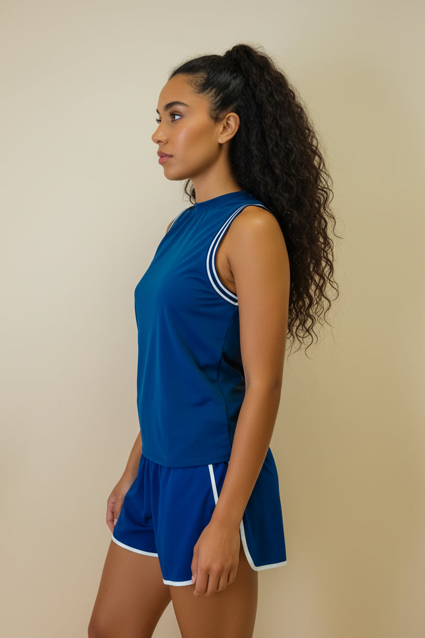 Woman wearing a blue athletic outfit with white trim on a beige background