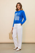 Blue sweater with American flag design worn by a person on a beige background