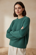 Woman wearing a teal sweater against a beige background
