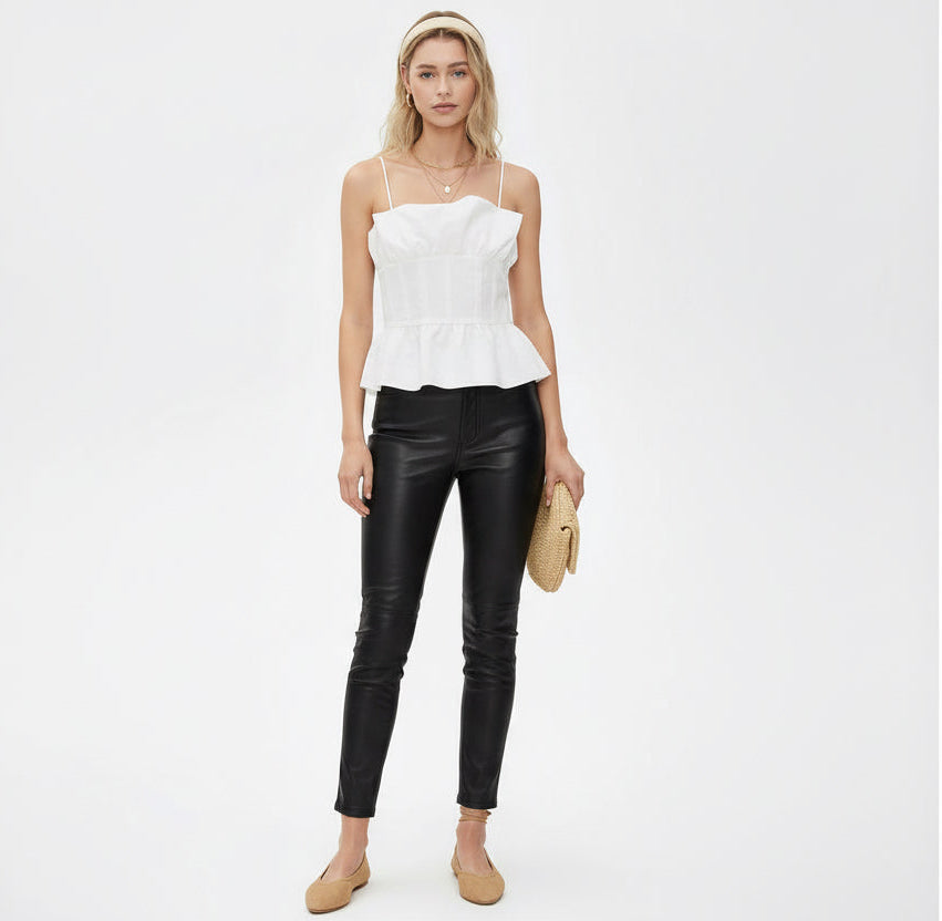 Woman wearing a white strapless top and black leather pants on a white background